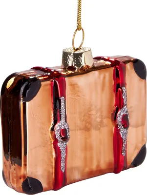 A close-up of a glass Christmas ornament shaped like a vintage suitcase.