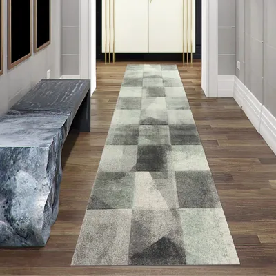 A long hallway with a runner rug, a bench, and cabinets.