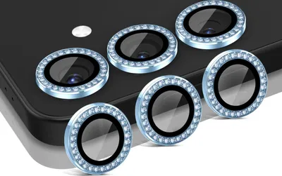 A set of camera lens protectors with decorative rhinestones on a dark surface.