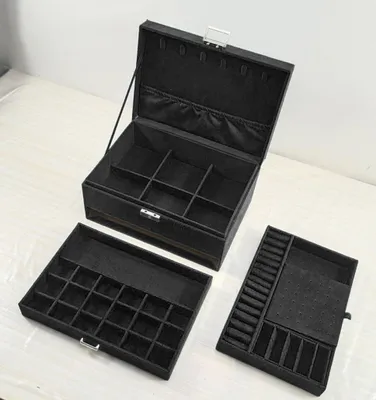 A black jewelry box with multiple compartments, shown open with two trays pulled out.