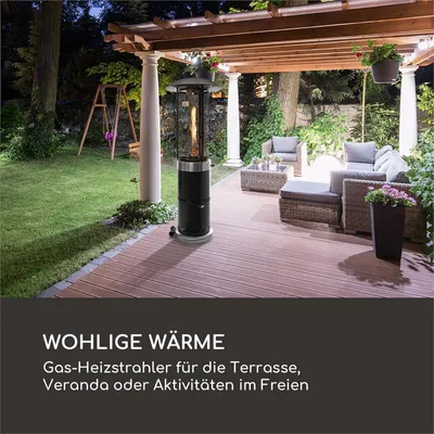 A patio heater is shown on a wooden deck at night, with outdoor furniture and a lawn visible in the background.