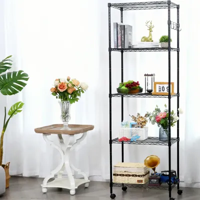 A black metal shelving unit with five shelves, decorated with various items, stands next to a small table with a vase of flowers.