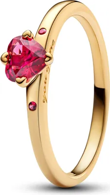 A close-up studio shot of a gold ring with a heart-shaped red gemstone.