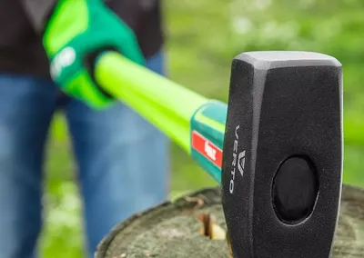 A person is using a sledgehammer to split a log.