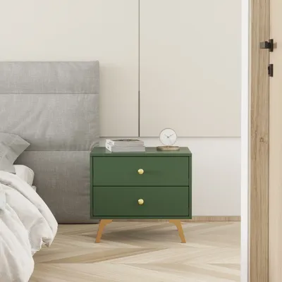A green nightstand with gold hardware sits next to a bed with a gray headboard and white bedding.