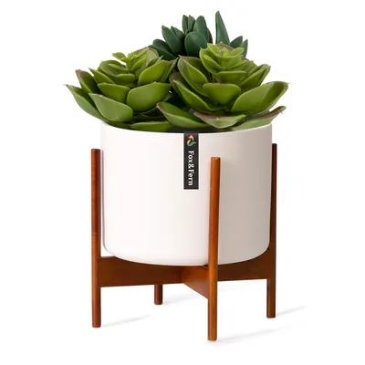 A white ceramic planter with artificial succulents on a wooden stand.