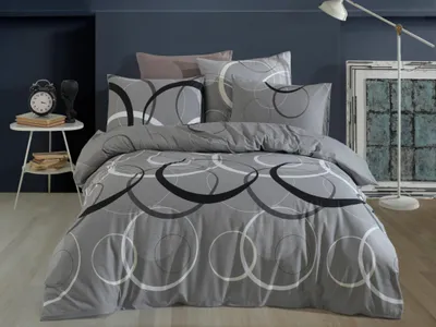 A bed with grey bedding featuring a circular pattern, set against a dark blue wall.