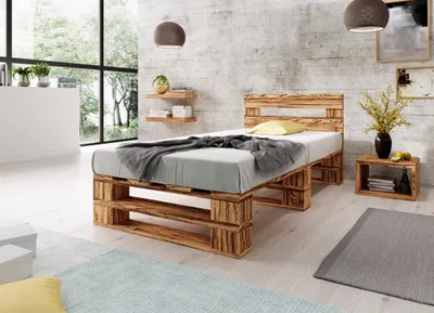 A bedroom with a bed made of wooden pallets, a bedside table, and shelves on the wall.