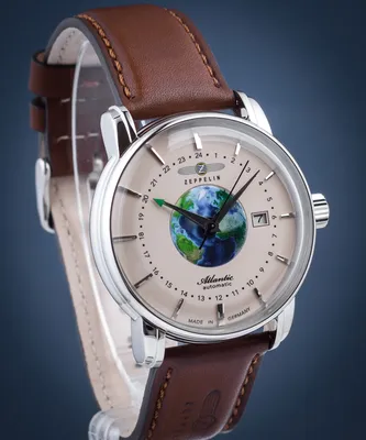 A close-up studio shot of a men's wristwatch with a brown leather strap and a dial featuring a globe.
