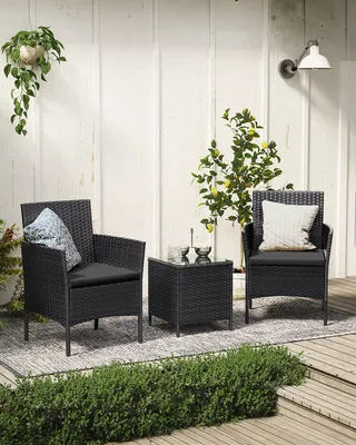 A black rattan furniture set with two chairs and a table on a patio.