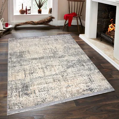 A rug is placed on a wooden floor in front of a fireplace.