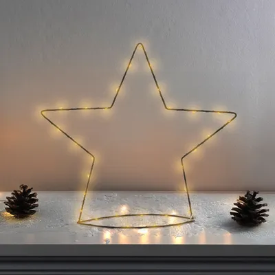 A star-shaped light decoration with pine cones on a shelf.