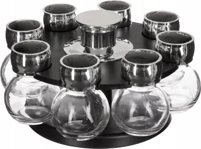 A rotating spice rack with eight glass jars and silver lids.