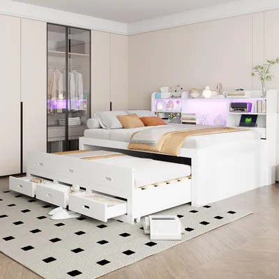 A bedroom scene featuring a white daybed with a pull-out trundle, a headboard with LED lighting, and storage drawers. The room also includes a wardrobe with clothes inside.
