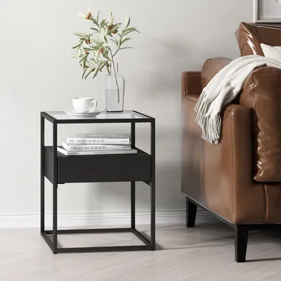 A black side table with a glass top sits next to a brown leather sofa with a white throw blanket.