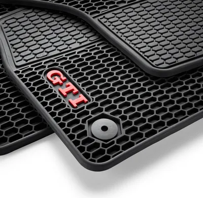 A close-up view of black car floor mats with a honeycomb pattern and a red 'GTI' logo.