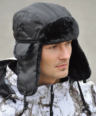 A man wearing a black pilot's hat and a camouflage jacket.