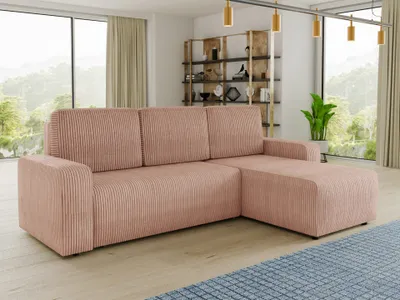 A pink corduroy sectional sofa is placed in a modern living room with large windows overlooking a natural landscape. A bookshelf filled with decorative items and a potted plant are visible in the background.