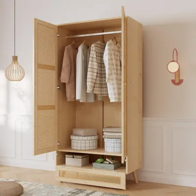 An open wooden wardrobe with clothes hanging inside and boxes on shelves.