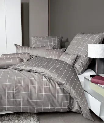 A neatly made bed with grey and white checkered bedding, including a duvet and pillows, in a modern bedroom setting.