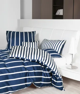 A neatly made bed with striped bedding and pillows.