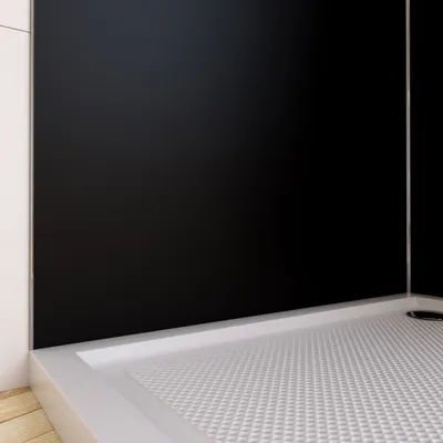 A close-up view of a shower tray with a black wall panel behind it.