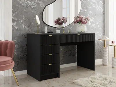 A vanity table with drawers and a mirror, decorated with flowers and cosmetics, in a room with textured wallpaper.