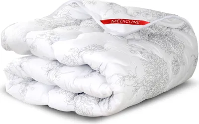 A folded white comforter with a gray floral pattern and a red tag with the brand name.