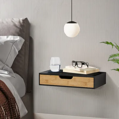 A bedside table with a drawer next to a bed, with a glass of water and books on top.