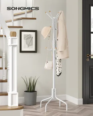 A white coat rack with several items hanging on it, placed in a hallway next to a staircase and a potted plant.