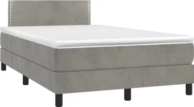 A studio shot of a gray box spring bed with a white mattress and a gray headboard.