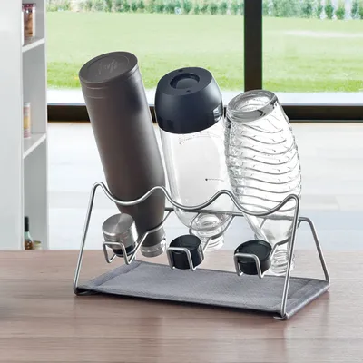 A kitchen counter with a bottle drying rack holding three bottles.