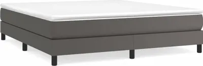 A studio shot of a gray box spring bed with a white mattress on top, set against a white background.