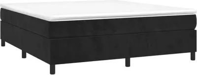 A studio shot of a black boxspring bed frame with a white mattress on top, set against a white background.