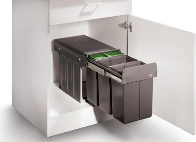 A pull-out waste bin system with multiple compartments inside a white cabinet.