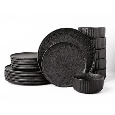 A set of black ceramic plates and bowls stacked against a white background.