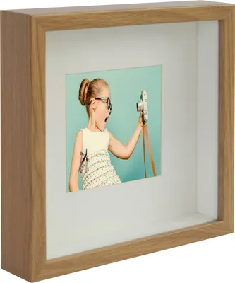 A shadow box frame with a picture of a young girl holding a camera.