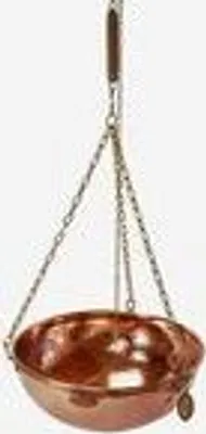 A copper bowl hanging from chains with a wooden handle.