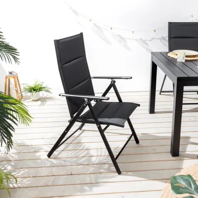 An outdoor garden chair is shown on a wooden deck with plants and string lights in the background.