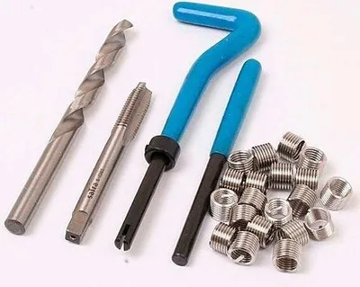 A set of tools for creating screw threads, including a drill bit, a tap, two insertion tools, and a pile of threaded inserts.