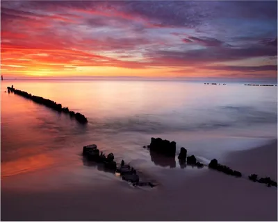 Produktbild von Wallario Poster - Sandstrand im Sonnenuntergang - Roter Himmel, Kunstdruck Größe: 40 x 50 cm