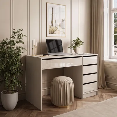 A modern desk setup in a well-lit room with a plant, laptop, and artwork.
