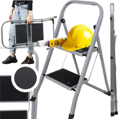 A person is holding a folded ladder, with a yellow hard hat and a level on the ladder.