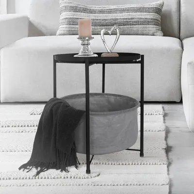 A side table with a basket and a blanket next to a sofa.