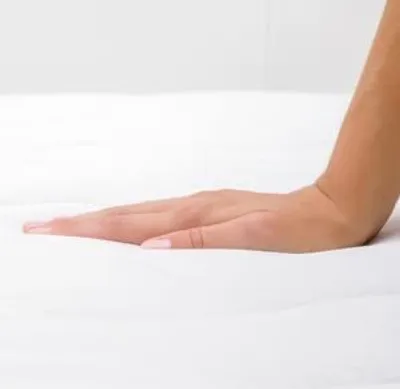A hand pressing down on a white mattress.