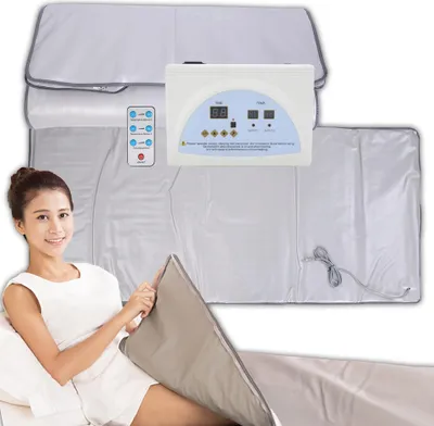 A woman is lying down with a sauna blanket wrapped around her legs, and a control panel is visible.