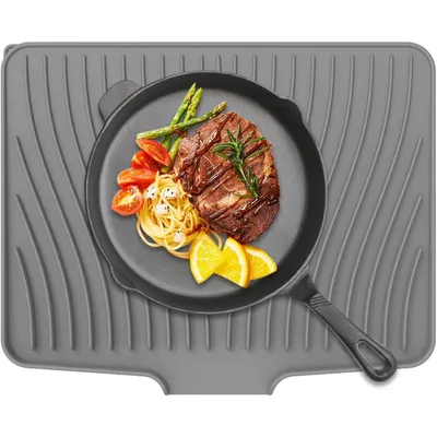 A steak dinner is served on a cast iron pan placed on a grey silicone drying mat.
