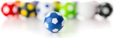 A single blue and white soccer ball in the foreground, with a blurred line of other colorful soccer balls in the background.