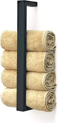 A black metal towel rack holding four rolled beige towels, mounted on a white wall.