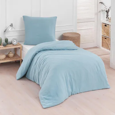A light blue duvet and pillow set laid out on a bed in a bedroom setting.